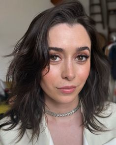 a close up of a person wearing a white shirt and silver choker on her neck