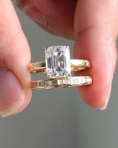 a woman's hand holding an engagement ring with a large emerald stone in it