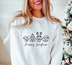 a woman standing next to a christmas tree wearing a white sweatshirt that says merry workshop