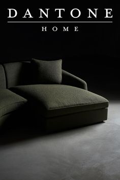 a couch sitting on top of a black floor next to a dark wall with the words dantone home