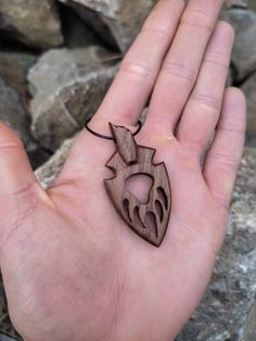 a person's hand holding a wooden pendant