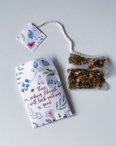 the tea bag is next to some cards and a necklace on a white table top