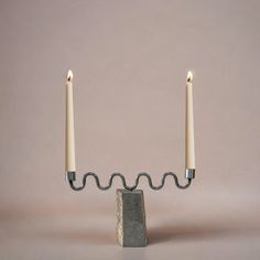 two candles are connected to a stone block