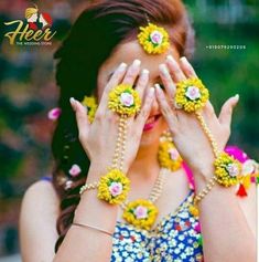 a woman covering her eyes with yellow flowers on her head and bracelets around her hands