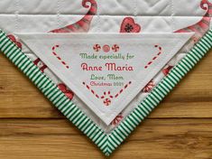 a white and green quilted triangle on top of a wooden table with an ornament in the center