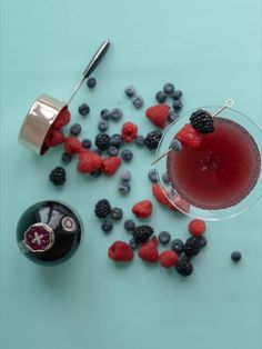 A top view of a martini glass filled with Chambord gin cocktail, a Chambord liqueur bottle and spread some berries on a light green table. Berry Martini, Eggnog Martini, Chambord Liqueur, Gin Recipes, Gin Cocktail Recipes, Martini Recipe