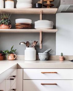 a kitchen with white cabinets and shelves filled with dishes