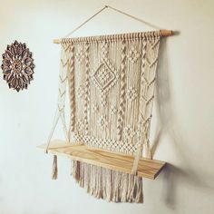 a macrame hanging on a wall next to a wooden shelf