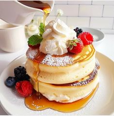 a stack of pancakes topped with whipped cream and berries