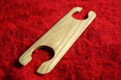 a bottle opener sitting on top of a red cloth next to a wooden handle with a hole in it