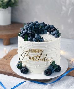 a white cake with blueberries and blackberries on top