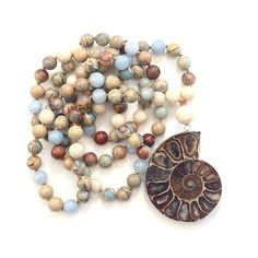 "Ammonite Mala Bead Necklace - African Opal, Riverstone, Sky Blue Jade - 108 Beads - 8mm Size Mala - Length Approx. 40\" long - Removable tassel Embody the spirit of Mother Nature with this Ammonite and African Opal Mala Bead necklace from True Nature Jewelry. Ammonite Fossil symbolizes continual change and evolution. Hand knotted for flexibility this Mala features African Opal to help ease emotional stresses and Riverstone to help energize your whole being along with Sky Blue Jade which wards o Earthy Beaded Necklace With 108 Beads For Healing, Nature-inspired Hand-strung Beaded Necklaces For Healing, Nature-inspired Beaded Necklaces With Natural Stones, Nature-inspired Beaded Necklaces With Round Natural Stones, Artisan Hand Knotted Beaded Necklaces With Round Beads, Artisan Hand Knotted Beaded Necklace With Round Beads, Artisan Hand Knotted Beaded Necklaces, Artisan Hand-knotted Beaded Necklace With Round Beads, Hand-strung Nature-inspired Beaded Necklaces