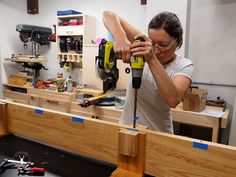 a woman using a power drill to cut wood