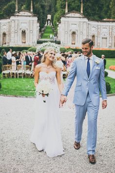 a bride and groom holding hands in front of an outdoor wedding venue with lots of people