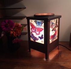 a lamp that is on top of a wooden table next to flowers and a potted plant