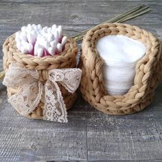 two baskets with white and pink flowers in them on a wooden table next to some twine