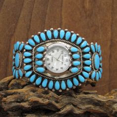 "Sterling silver and block turquoise cluster watch bracelet. The width is 1 7/8\". The cuff measures 5 3/4\" with a 1 1/8\" gap. There is a watch mounted in the band for display. We do not offer a watch guarantee. It is working now. It is a quartz watch with a mother-of-pearl face. The fans which cover the pins have 4 stones each. There are 28 stones around the edge of the bracelet. The cluster on each side has 11 stones. The inside is stamped RLD (Zuni Diane Lonjose). The watch cuff is in good 11 Stone, Cuff Watch, Watch Bracelet, Luxury Watches For Men, 11 11, Luxury Watches, Quartz Watch, Mother Of Pearl, Watch Bands