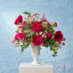 a white vase filled with red and pink flowers