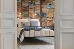 an open door leading to a bed with lots of boxes on the wall