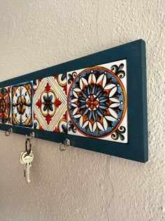 a wall hanging with several different designs and keys attached to the hooks on it