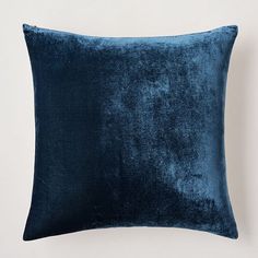 a blue velvet pillow on a white wall