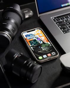 an open laptop computer sitting on top of a desk next to a phone and camera