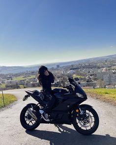 a woman sitting on top of a black motorcycle