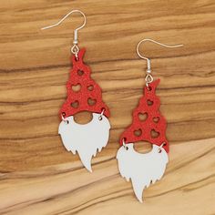 red and white gnome earrings on wooden surface