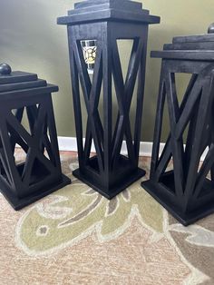 three black candle holders sitting on top of a carpet