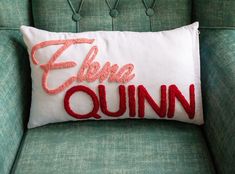 an embroidered pillow that says,'eloquinn'on the back of a green chair