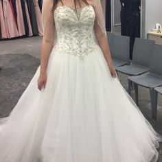 a woman standing in front of a mirror wearing a wedding dress with beading on it