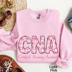 a pink shirt with the word cna printed on it next to shoes and sunglasses