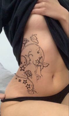 a woman's stomach with tattoos on it and stars in the bottom part of her belly