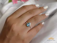 a woman's hand wearing a ring with a blue topazte on it