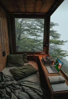 there is a bed with green sheets and pillows in front of a window that looks out onto the water