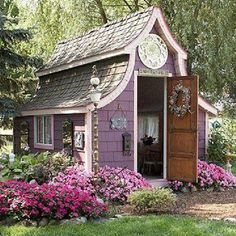 a small purple house with pink flowers around it