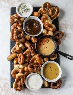 an assortment of pretzels, dips and sauces on a platter