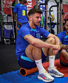 a man sitting on top of a blue mat in front of a gym equipment rack