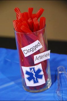 a glass filled with red onions sitting on top of a blue table covered in labels