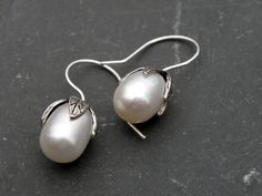 "Stunning, genuine freshwater pearls 8.9 ct. each! The teardrop pearls are AAA grade with brilliant luster and outstanding bright white color. Handcrafted artisan flower caps and handcrafted ear wires complete the unique, organic look of this chic and elegant earrings. They are about 1 \" long." Oval White Gold Pearl Earrings For Wedding, White Oval Pearl Earrings, Elegant Handmade Oval Pearl Earrings, Flower Pearl Drop Earrings For Anniversary, White Oval Pearl Earrings With Pearl Charm, White Oval Pearl Earrings With Charm, White Pearl Earrings, Silver Heart Earrings, White Pearl Earring