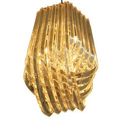 a gold colored light fixture hanging from a metal hook on a white background with clippings