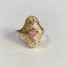 Stunning antique 14k yellow gold pink tourmaline and genuine diamond filigree shield ring!! This incredible piece boasts a gorgeous princess cut pink tourmaline weighting .71 cts and 2 sparkling diamonds, which have a combined weight of approximately .25 cts. The setting boasts pierced scrolling filigree and chased designs. Beautiful piece of fine vintage statement jewelry, circa 1920s! ERA - Circa 1920s, Art Deco Era METAL / MATERIAL - 14k yellow gold, princess cut pink tourmaline (approx. .71 Art Deco Shield Ring, Antique Pink Rose Cut Diamond Rings, Antique Pink Diamond Rings, Antique Yellow Gold Ruby Ring With Filigree, Vintage 14k Gold Pink Rings, Vintage Pink Ruby Ring In 14k Gold, Pink Hallmarked Victorian Ruby Ring, Victorian Pink Hallmarked Ruby Ring, Pink Victorian Hallmarked Ruby Ring