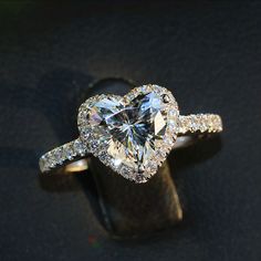 a heart shaped diamond ring on top of a piece of wood with diamonds around it