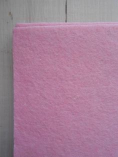 a piece of pink felt sitting on top of a wooden floor next to a white wall