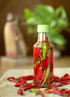 a bottle filled with red peppers sitting on top of a table