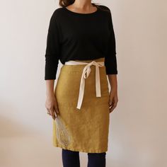 a woman standing in front of a white wall wearing a brown skirt and black top