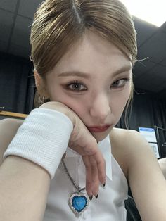 a young woman sitting at a table with her hand on her chin