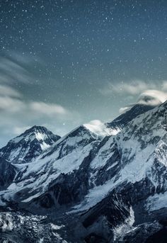 snow covered mountains under a night sky with stars in the sky and clouds above them