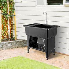 a black sink sitting on top of a wooden stand next to a building and green grass