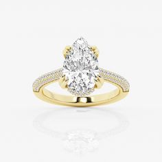 a yellow gold engagement ring with a pear shaped diamond in the center and pave set shoulders